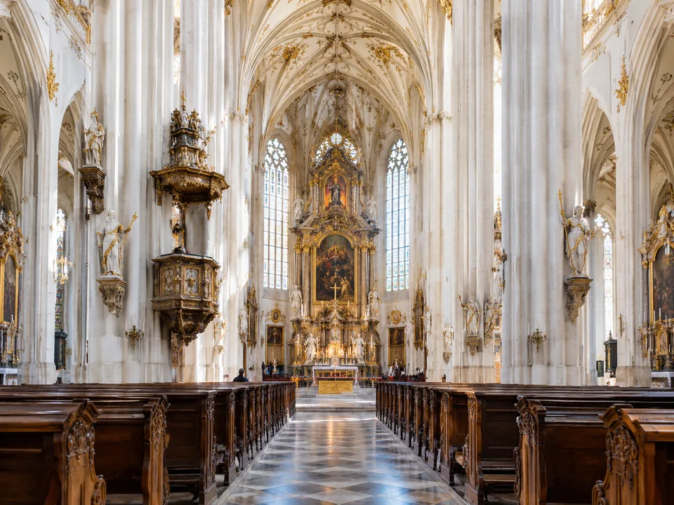A white and gold church interior with tall columns and empty pews
