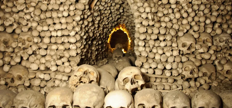 Rows of skulls stacked in an arch under a lamp