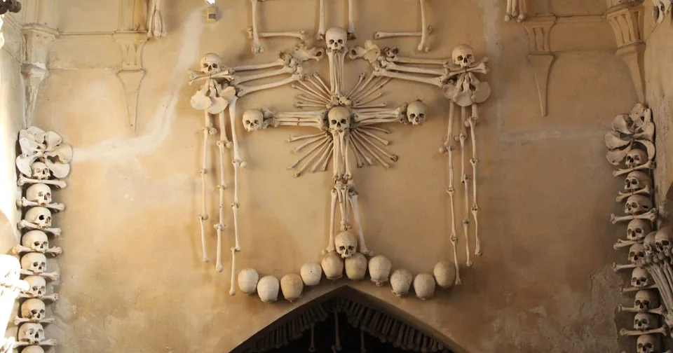 A cross and skulls made of bones on a pale wall